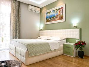 ein Schlafzimmer mit einem großen weißen Bett in einem Zimmer in der Unterkunft Hotel Vila Verde City Center in Tirana