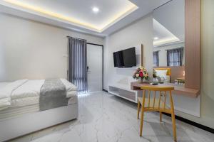 Dormitorio con cama, escritorio y TV en Tree Homestay Mitra RedDoorz en Kasri