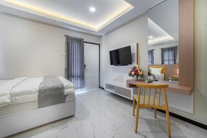 una camera con letto, scrivania e TV di Tree Homestay Mitra RedDoorz a Kasri