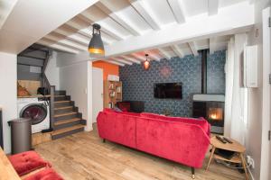 a living room with a red couch and a staircase at L’Ancre des falaises - MAISON VUE MER & À 50M PLAGE (hypercentre) in Étretat