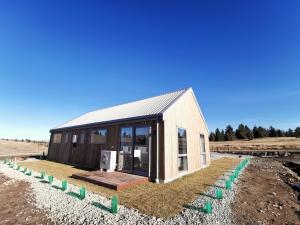 uma pequena casa com um telhado de metal num campo em Skyrim Lodge em Lake Tekapo