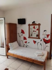 1 dormitorio con 1 cama con flores rojas en la pared en Alexandra rooms, en Skala Potamias