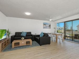 a living room with a couch and a table at Kingy Beach Getaway with Balcony - Central Kingscliff in Kingscliff