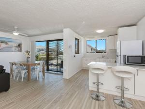 a kitchen with white appliances and a table with chairs at Kingy Beach Getaway with Balcony - Central Kingscliff in Kingscliff