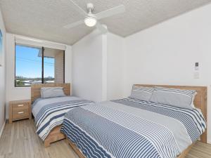 two beds in a bedroom with a ceiling fan at Kingy Beach Getaway with Balcony - Central Kingscliff in Kingscliff