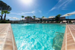 uma piscina com água azul e guarda-sóis brancos em Insula Boutique Hotel em Procida