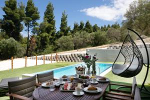 a table with food on it next to a pool at The Euphoria Club Luxury Villas in Pefkohori