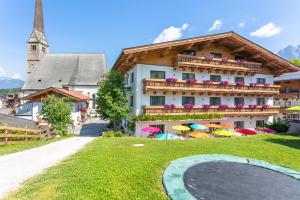 un edificio con balcón con sombrillas en el césped en Pension Pinzgauer Hof, en Maria Alm am Steinernen Meer