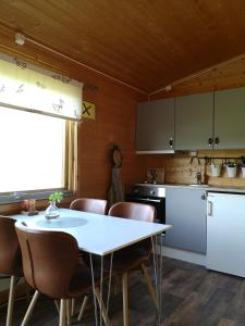 a kitchen with a white table and chairs and a table and a counter at Davvi Siida - Reindeer Design Lodge in Kjøllefjord