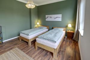 two beds in a room with green walls and wooden floors at fewo1846 - Angelburg - komfortable Wohnung im Stadtzentrum in Flensburg