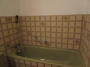 a green bath tub in a tiled bathroom at good bed Aarwangen in Aarwangen