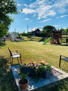 un parc avec un banc, des fleurs et une aire de jeux dans l'établissement Platán Apartmanház, à Balatongyörök