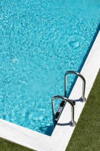una piscina con una escalera de metal en el agua en The Euphoria Club Luxury Villas en Pefkohori
