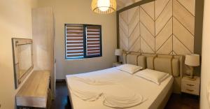 a bedroom with a white bed with a wooden headboard at Gradina Forest Villas in Sozopol
