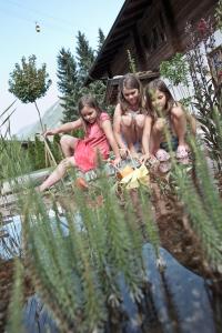 tres chicas sentadas en el borde de un cuerpo de agua en Brugger ChaletDorf, en Mayrhofen