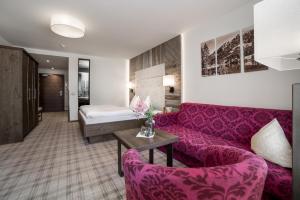 a living room with a purple couch and a bed at Kohlerhof - 4 Star Wellness & Active Hotel in Fügen