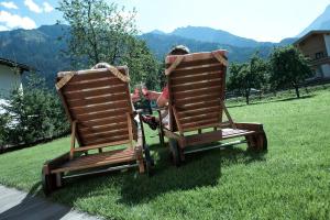 een meisje zittend in twee schommelstoelen in het gras bij Brugger ChaletDorf in Mayrhofen
