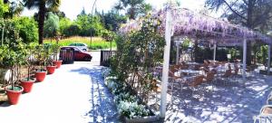 einen Garten mit einer Pergola mit lila blühenden Pflanzen in der Unterkunft Hotel Prati in Castrocaro Terme