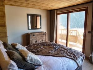 Schlafzimmer mit einem Bett mit einem Spiegel und einem Fenster in der Unterkunft Astraea in Peisey-Nancroix
