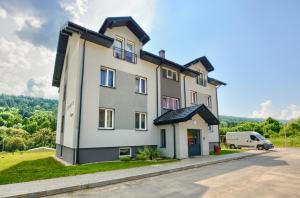 una gran casa blanca con un coche aparcado delante de ella en Apartament Glamour en Ustrzyki Dolne