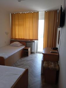a room with two beds and a desk and a window at Hotel Park in Burgas City