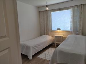 een kleine slaapkamer met 2 bedden en een raam bij Yyterin valkoinen huoneisto 14A talo B 21 in Pori