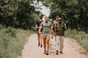 Eine Gruppe von Männern, die auf einer unbefestigten Straße spazieren in der Unterkunft Phelwana Game Lodge in Hoedspruit