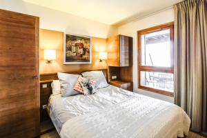 um quarto com uma cama e uma janela em 2 Bed Ski in and Ski out Luxury Apt in 5 star Residence em Flaine