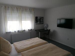 a bedroom with two beds and a television and a desk at Sleep & Living FeWo Rheinsheim in Philippsburg