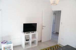 a living room with a tv on a white stand at Casa Do Tio Arménio in Ponte de Lima