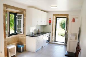 a kitchen with white cabinets and a sink at Casa Do Tio Arménio in Ponte de Lima