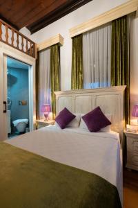a bedroom with a large white bed with purple pillows at Cedrus Hotel in Antalya