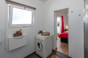 uma lavandaria com uma máquina de lavar roupa e uma janela em Chez Nous em Sintra