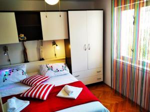 een slaapkamer met 2 bedden met rode en witte kussens bij Apartments LukaS in Tisno