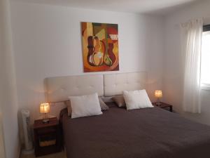 a bedroom with a bed with two lamps and a painting at Casa Para Ti Delfinesse in Puerto del Carmen