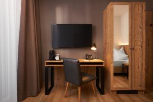 a living room with a wooden table and a television at Hyperion Hotel Garmisch – Partenkirchen in Garmisch-Partenkirchen
