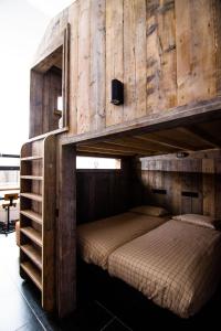 Café Coureur Houffalize في هوفاليز: غرفة نوم مع سرير بطابقين مع جدران خشبية