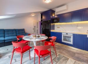 a kitchen with blue cabinets and a white table and red chairs at Seaman's house in Burgas