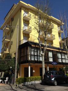ein vor einem gelben Gebäude geparkt in der Unterkunft Hotel Busignani in Rimini