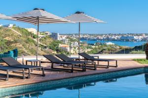 een groep stoelen en parasols naast een zwembad bij Calallonga Hotel Menorca in Mahón