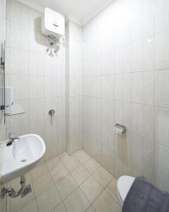 a white bathroom with a sink and a toilet at Heritel Urban Hostel in Jakarta