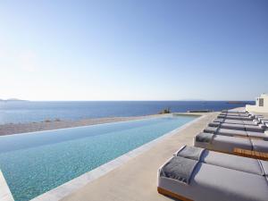 a swimming pool with lounge chairs and the ocean at Domes White Coast Milos, Adults Only - Small Luxury Hotels of the World in Mytakas
