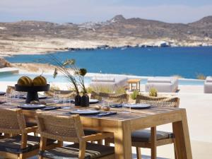 a wooden table and chairs with a view of the ocean at Domes White Coast Milos, Adults Only - Small Luxury Hotels of the World in Mytakas