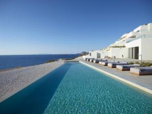 a swimming pool next to a building with the ocean at Domes White Coast Milos, Adults Only - Small Luxury Hotels of the World in Mytakas