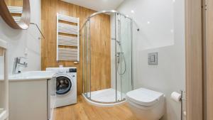 a bathroom with a shower and a washing machine at Apartamenty Sun & Snow Euronia in Pobierowo