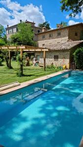ein großer Pool vor einem Steinhaus in der Unterkunft Locanda Quattro Vesta in San Casciano dei Bagni
