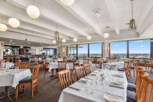 un restaurante con mesas y sillas blancas y ventanas en Comfort Inn The Lakes, en Mount Gambier