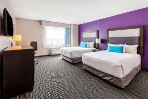 Habitación de hotel con 2 camas y pared púrpura en CHN Hotel Monterrey Aeropuerto, Trademark by Wyndham, en Monterrey
