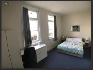 a bedroom with a bed and two windows at Malvern Backpackers in Melbourne