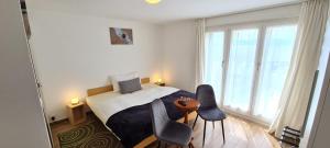 Schlafzimmer mit einem Bett mit 2 Stühlen und einem Tisch in der Unterkunft Hôtel Restaurant Cave Bel-Air in Praz